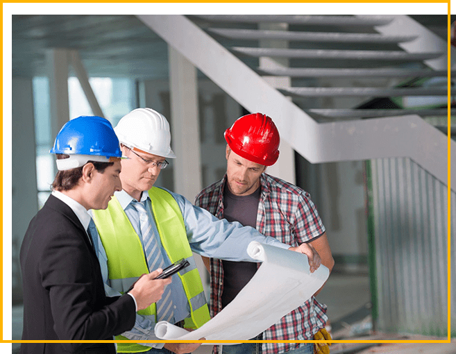 Three men in hard hats looking at a construction plan.