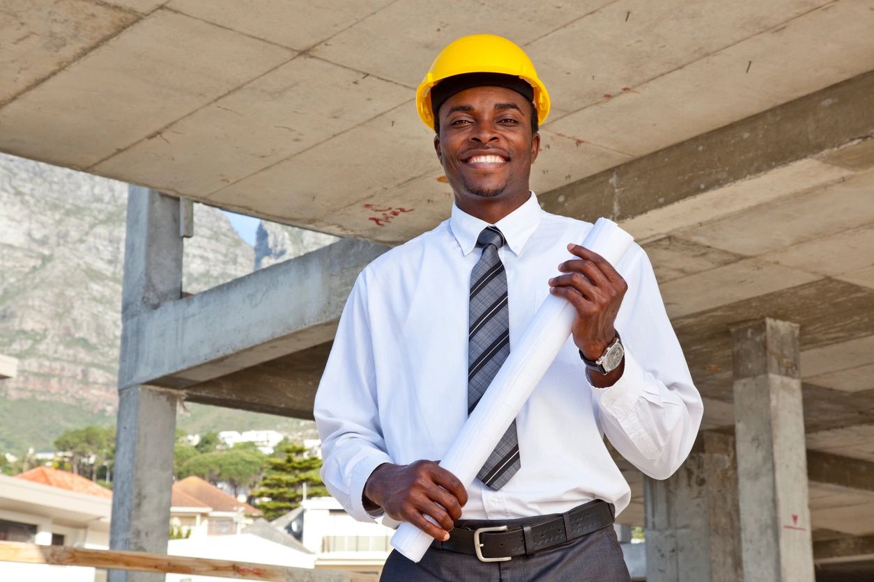 A man in a yellow hat and tie holding papers.